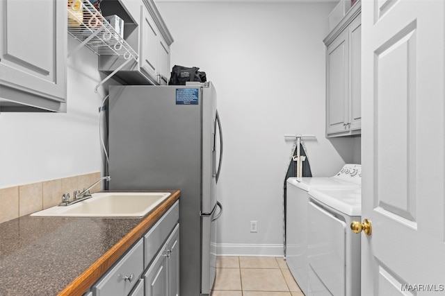 clothes washing area with sink, cabinets, light tile patterned flooring, and separate washer and dryer