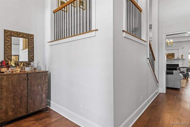 stairway featuring a high ceiling, a notable chandelier, and hardwood / wood-style flooring