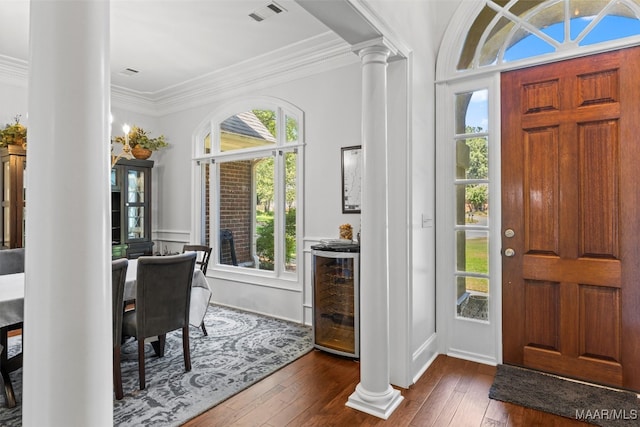 entryway with ornate columns, dark hardwood / wood-style floors, plenty of natural light, and ornamental molding