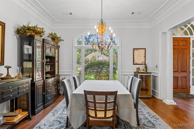 dining space with crown molding, dark hardwood / wood-style floors, a chandelier, and ornate columns