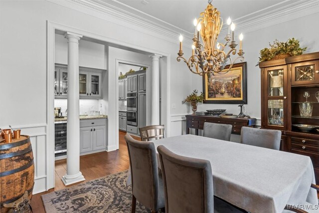 dining area with a notable chandelier, dark wood-type flooring, ornate columns, and crown molding