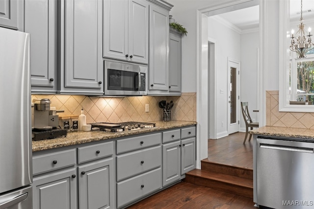 kitchen with stainless steel appliances, decorative backsplash, ornamental molding, dark hardwood / wood-style floors, and gray cabinetry