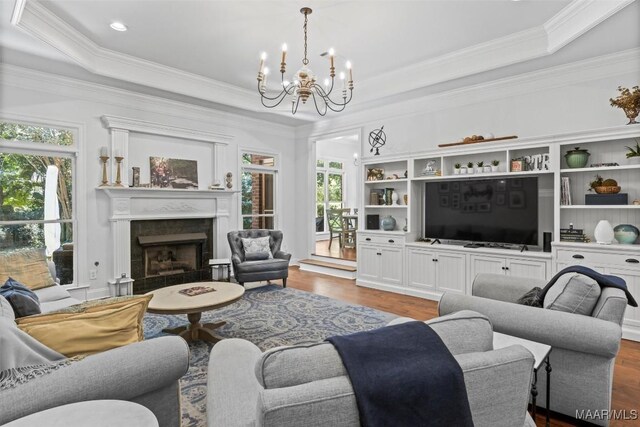 living room with hardwood / wood-style flooring, an inviting chandelier, a tray ceiling, and ornamental molding