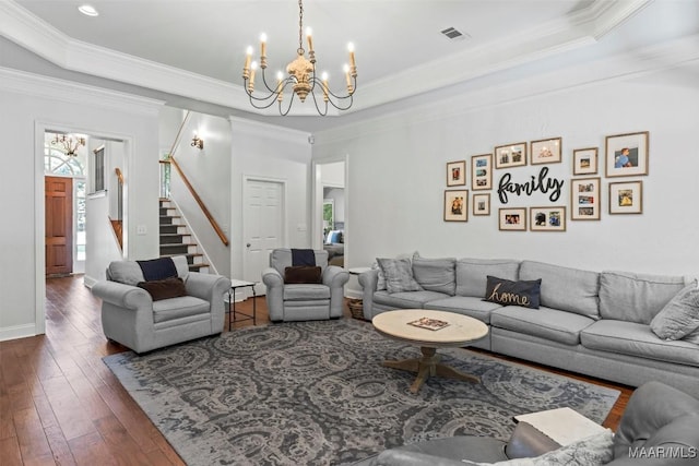 living room featuring dark hardwood / wood-style floors, a chandelier, crown molding, and a tray ceiling