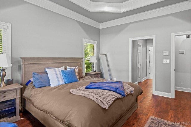 bedroom with a tray ceiling, dark wood-type flooring, and ornamental molding