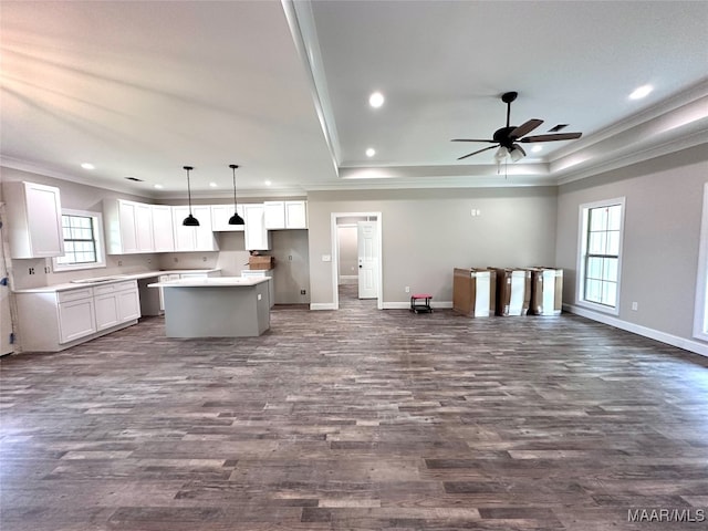 kitchen with dark hardwood / wood-style flooring, a center island, decorative light fixtures, white cabinets, and ornamental molding