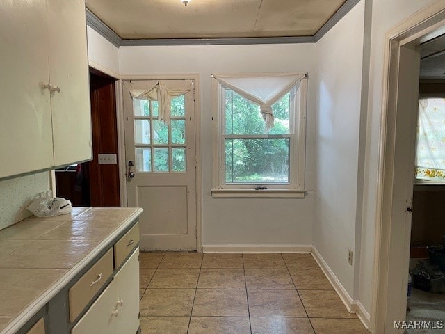 entryway with ornamental molding and light tile patterned floors