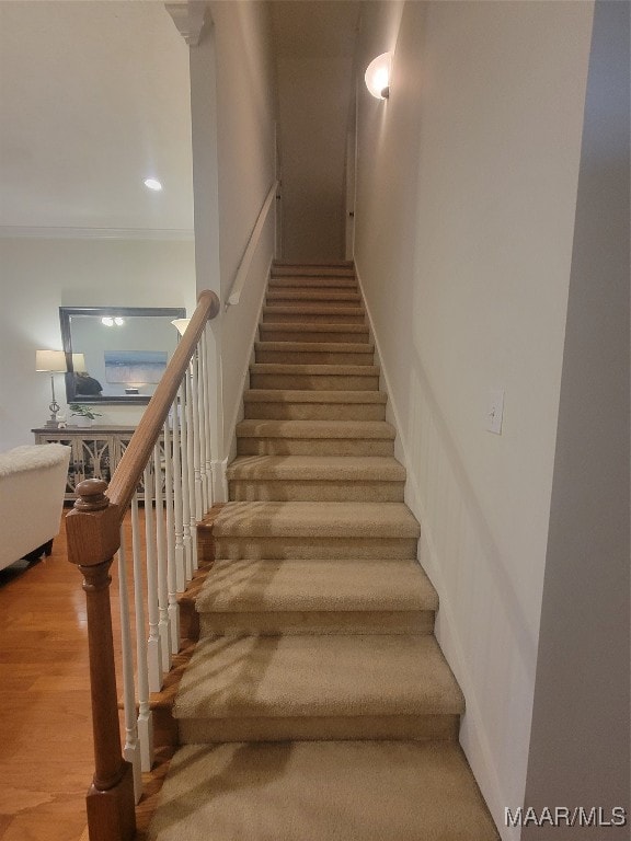 staircase featuring hardwood / wood-style flooring and crown molding