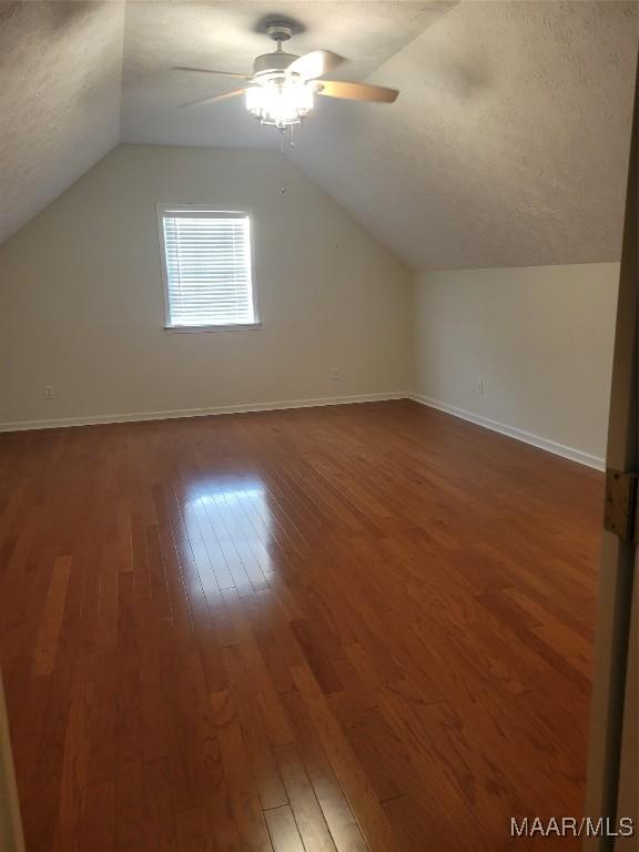 additional living space with vaulted ceiling, ceiling fan, hardwood / wood-style floors, and a textured ceiling