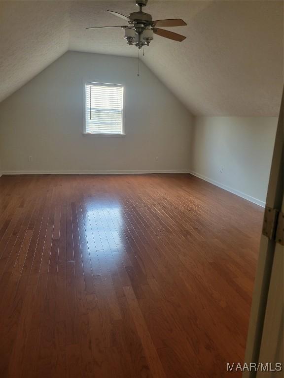 bonus room featuring ceiling fan, dark hardwood / wood-style flooring, lofted ceiling, and a textured ceiling