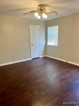 empty room featuring ceiling fan, baseboards, and dark wood-style flooring