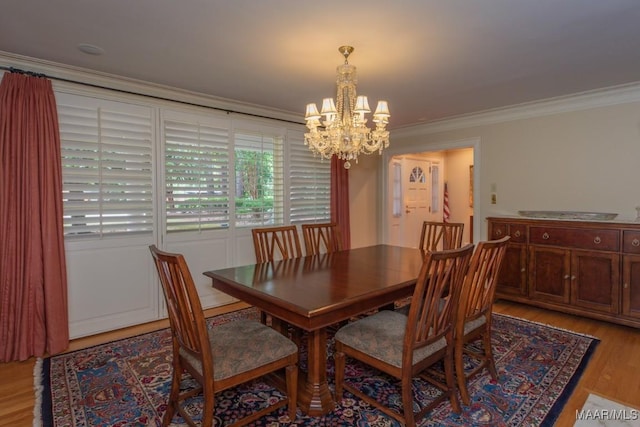 dining room featuring light wood finished floors, ornamental molding, and an inviting chandelier