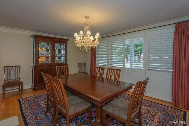 dining room with ornamental molding, wood finished floors, and a notable chandelier