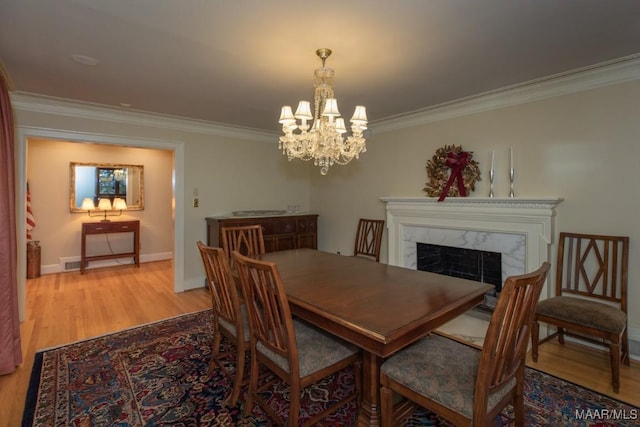 dining area featuring a premium fireplace, light wood-type flooring, and crown molding