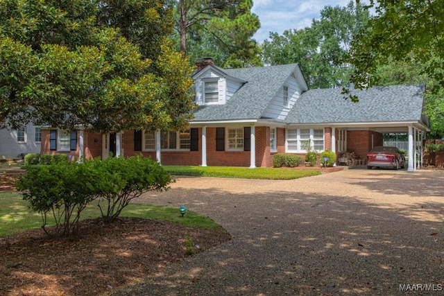 view of front of property with driveway, roof with shingles, a carport, and brick siding