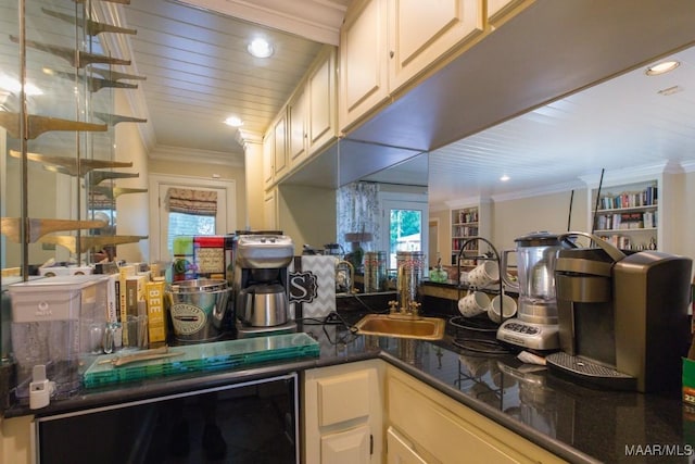 kitchen with dark countertops, wine cooler, crown molding, a sink, and recessed lighting