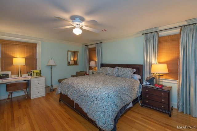 bedroom with light wood-type flooring, a ceiling fan, and crown molding