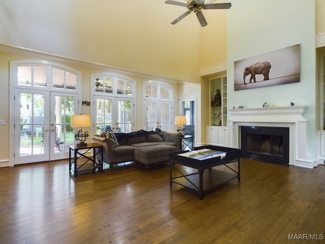 living room with french doors, dark wood-type flooring, built in shelves, and ceiling fan