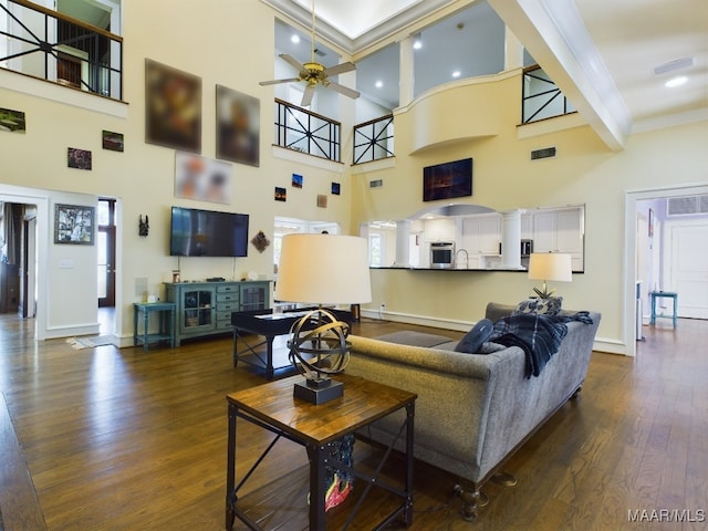 living room featuring beam ceiling, a towering ceiling, ceiling fan, and dark wood-type flooring