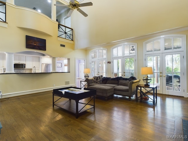 living room with dark hardwood / wood-style floors, a towering ceiling, ceiling fan, and french doors