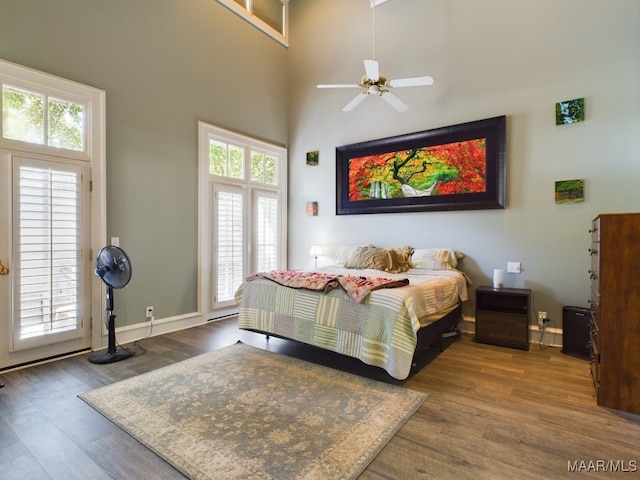 bedroom with ceiling fan, hardwood / wood-style floors, and a high ceiling