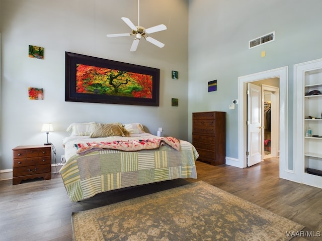 bedroom featuring a high ceiling, a spacious closet, dark hardwood / wood-style floors, and ceiling fan