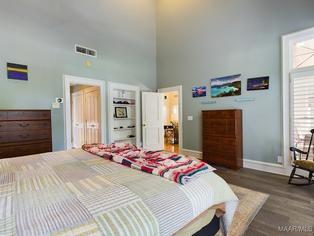 bedroom featuring a towering ceiling and dark hardwood / wood-style floors