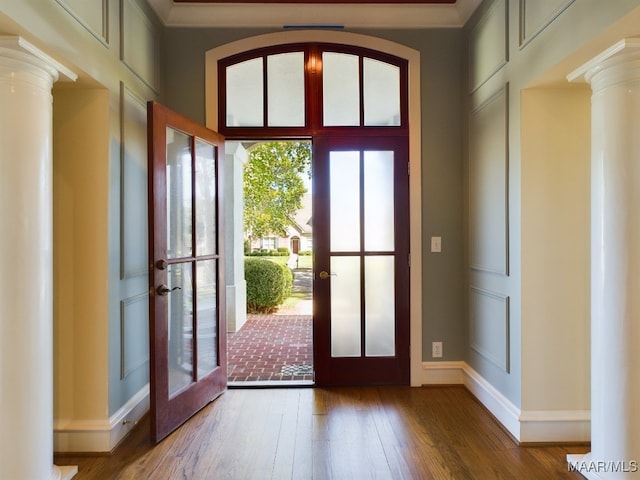 doorway with decorative columns, ornamental molding, french doors, and hardwood / wood-style flooring