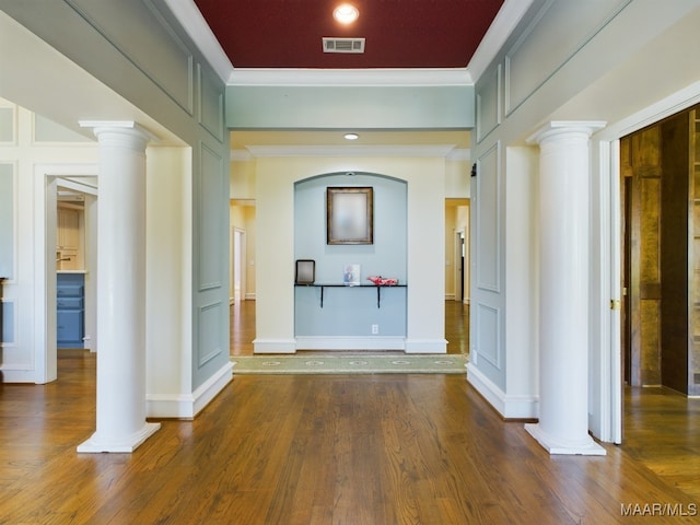 corridor featuring crown molding, decorative columns, and dark wood-type flooring