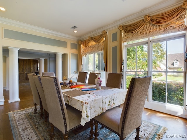 dining space featuring wood-type flooring, decorative columns, and plenty of natural light