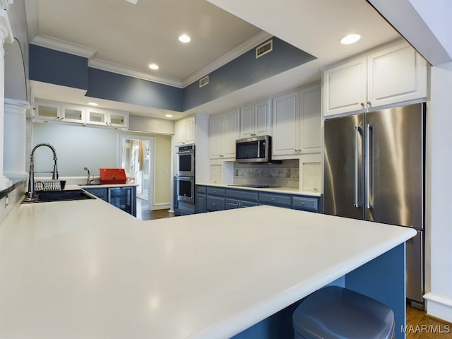 kitchen featuring white cabinetry, blue cabinetry, stainless steel appliances, crown molding, and sink