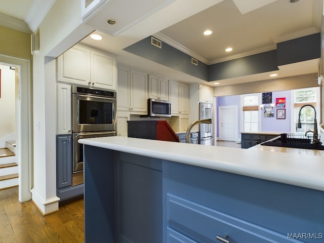 kitchen with white cabinets, ornamental molding, stainless steel appliances, and dark hardwood / wood-style flooring