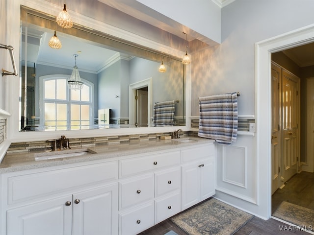 bathroom featuring ornamental molding, wood-type flooring, an inviting chandelier, and vanity