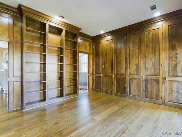 spare room with light hardwood / wood-style flooring and wood walls