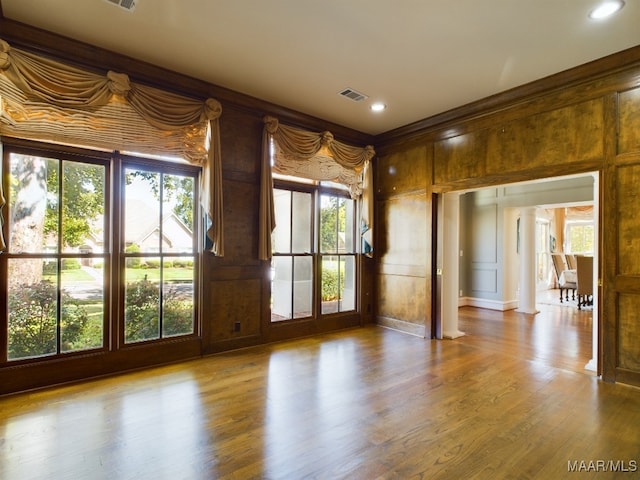 unfurnished room with light hardwood / wood-style floors and ornate columns