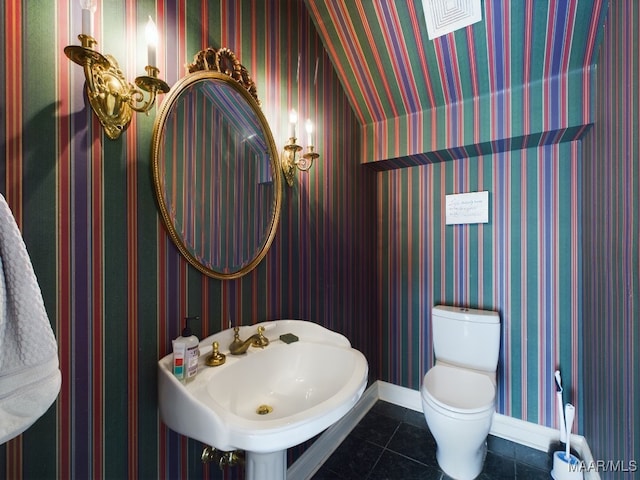 bathroom featuring tile patterned flooring, vaulted ceiling, toilet, and sink