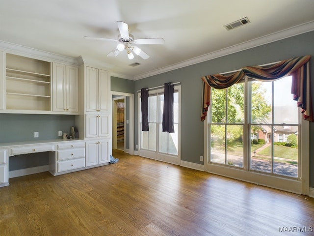 interior space with light wood-type flooring, built in desk, ceiling fan, and crown molding