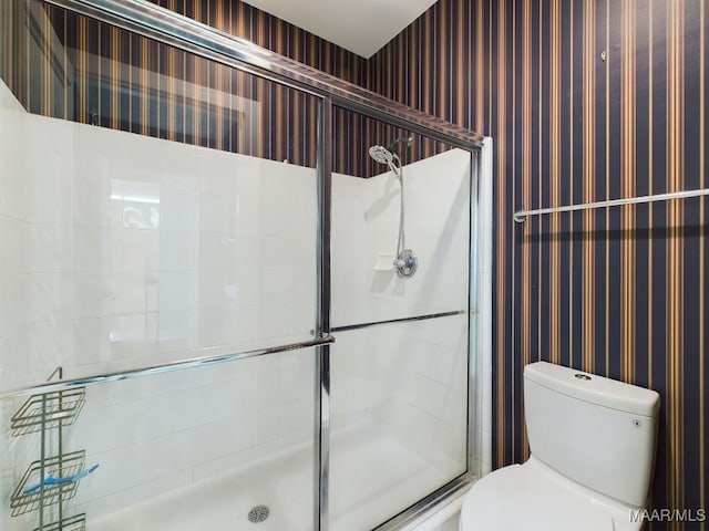 bathroom featuring a shower with shower door and toilet