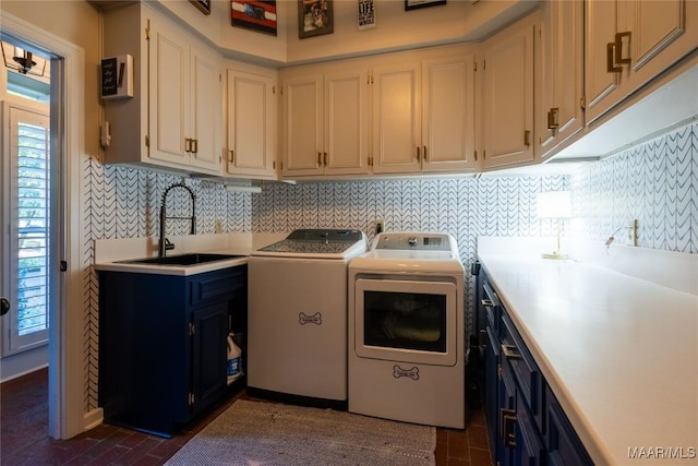 laundry room featuring brick floor, independent washer and dryer, a sink, and cabinet space