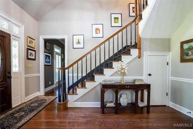 entryway featuring high vaulted ceiling, stairway, baseboards, and wood finished floors