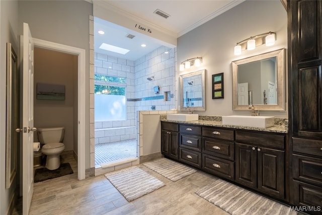 bathroom featuring toilet, vanity, tile walls, tiled shower, and crown molding