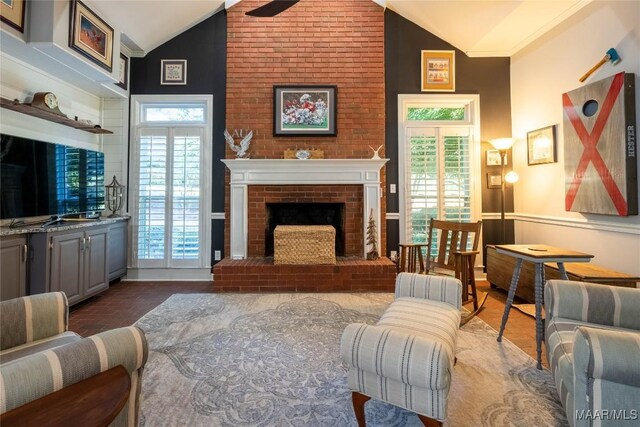 living room featuring high vaulted ceiling, brick wall, and a brick fireplace