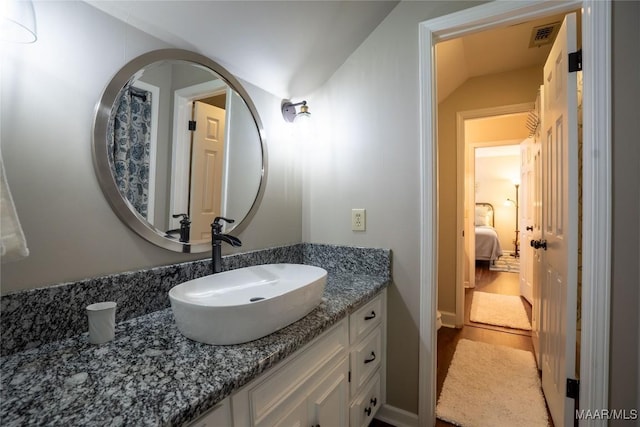 ensuite bathroom with ensuite bathroom, wood finished floors, vanity, and visible vents