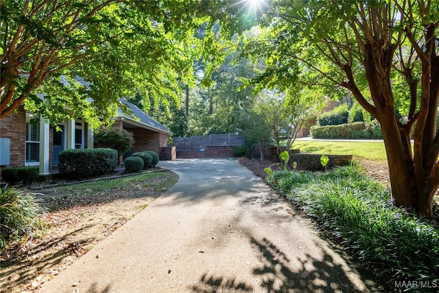 exterior space featuring driveway, fence, and brick siding