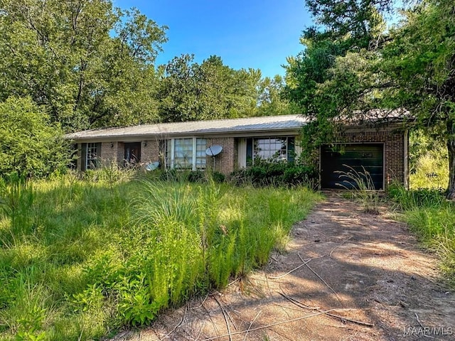 single story home with an attached garage, driveway, and brick siding