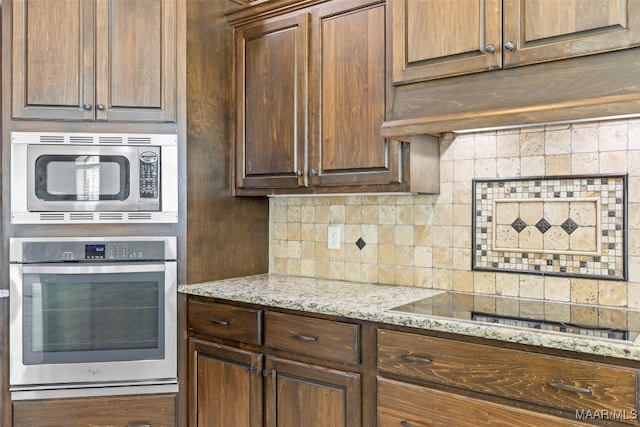 kitchen featuring stainless steel appliances, decorative backsplash, and light stone counters