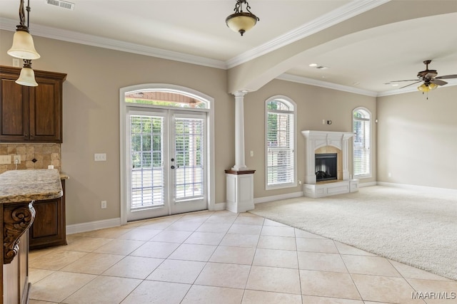 interior space featuring ornamental molding, french doors, decorative columns, ceiling fan, and light carpet