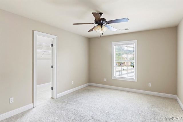 empty room with ceiling fan and light carpet