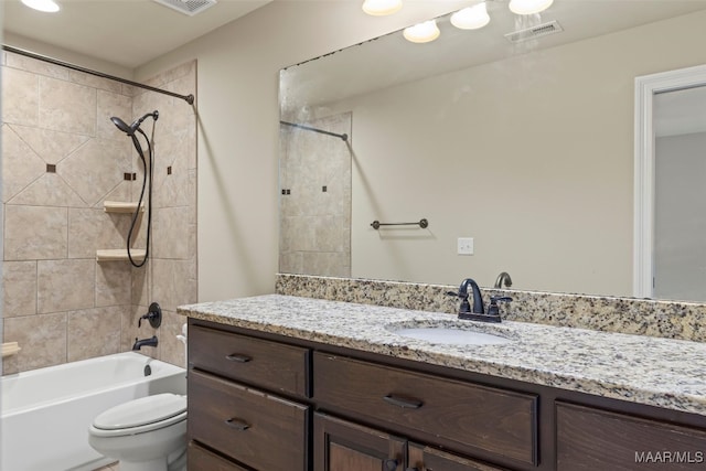 full bathroom featuring tiled shower / bath combo, toilet, and vanity