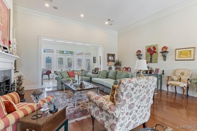 living area featuring crown molding, visible vents, a premium fireplace, wood finished floors, and baseboards